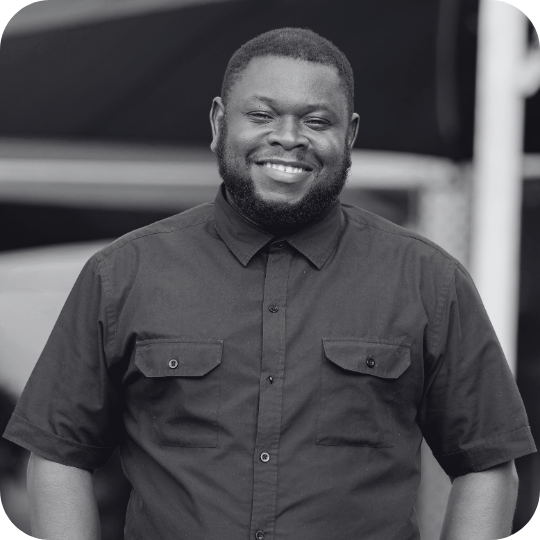 Black and white photo of a young man with a beard looking confidently at the camera.